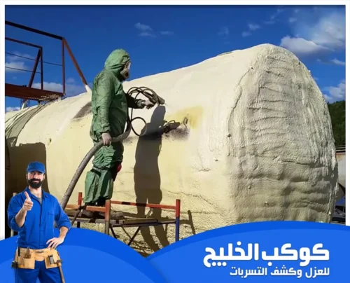 ترميم خزانات المياه في أبوظبي 0567121544 كوكب الخليج فنيًا يرش طبقة عزل فوم على السطح الخارجي لخزان كبير مع ارتداء معدات الوقاية.